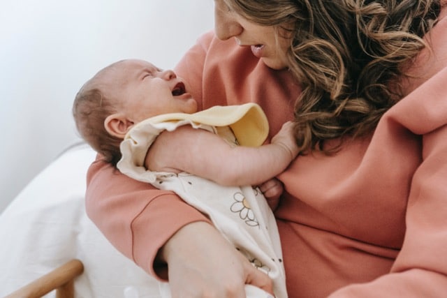 Woman with baby in hand shows stress and postpartum depression symptoms