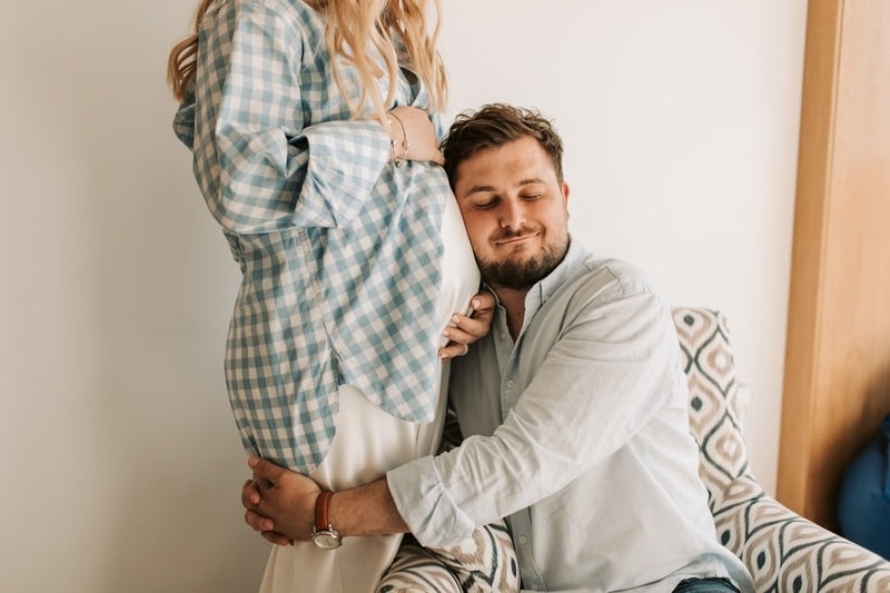 Pregnant woman with his husband hugging her tummy