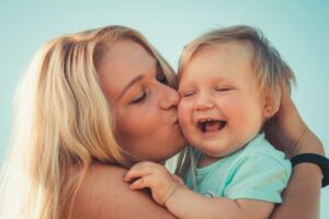 mom kissing her laughing baby