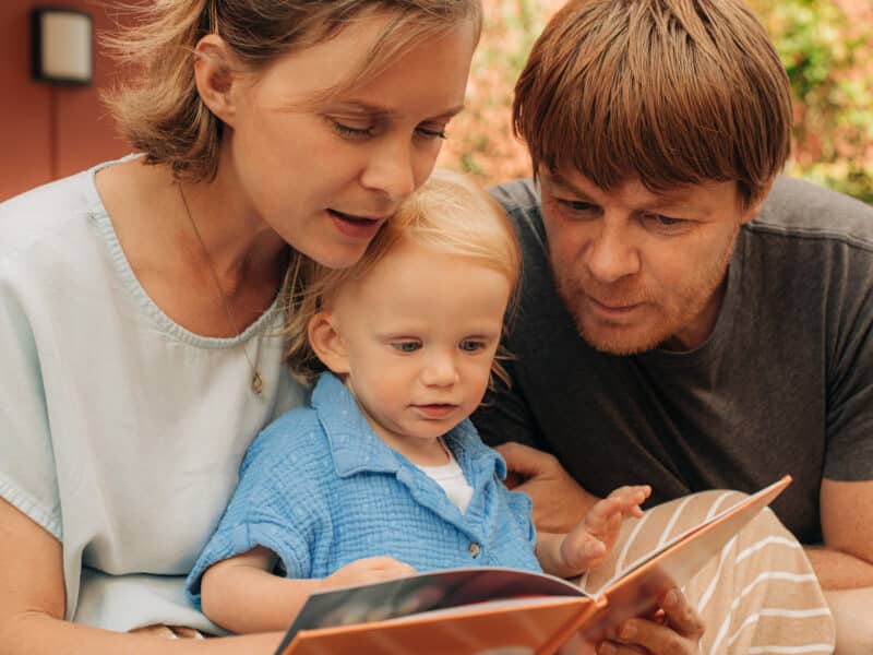 Portrait of happy family with kid reading book