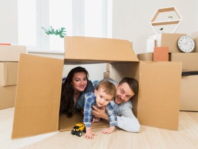 portrait of a happy parents playing with toddler boy inside the cardboard box