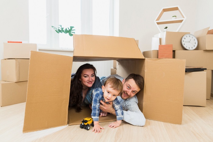 portrait of a happy parents playing with toddler boy inside the cardboard box