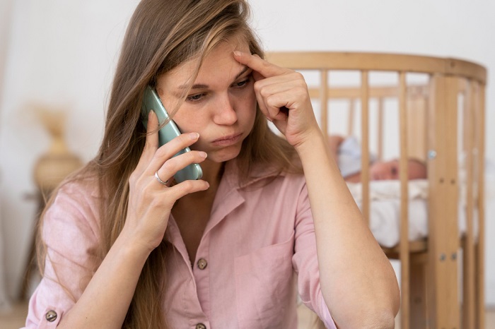 A worried mother talking on the phone, struggling with postpartum anxiety
