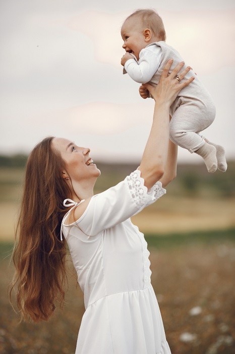 A joyful mother holds her smiling baby in her arms, creating a loving bond between them.